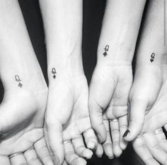 four people holding their hands together with tattoos on them