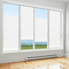 an empty room with white walls and wooden flooring, looking out to the ocean