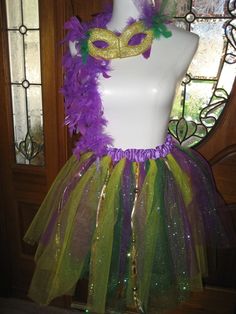 a white mannequin wearing a purple and green tutu skirt with gold sequins