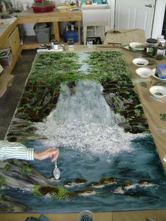 a man standing in front of a painting on top of a table