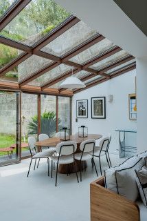 a living room filled with lots of furniture next to a large glass wall covered in windows