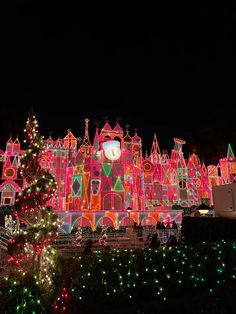 an elaborately lit castle with a christmas tree in the foreground