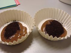 two cupcakes with chocolate frosting and sprinkles in paper cups