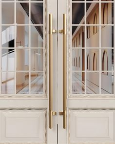 two doors with glass and gold handles in front of a white door that has windows on both sides