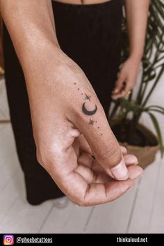 a person's hand with a crescent and stars tattoo on it, in front of a potted plant