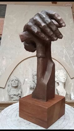 a sculpture of a hand holding a block of wood