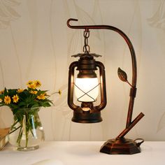 a lamp that is on top of a table next to a vase with flowers in it