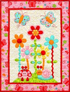 a quilted wall hanging with flowers and bugs on it's side, in pink