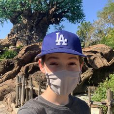 a young boy wearing a face mask in front of a tree at the disney world