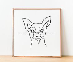 a black and white drawing of a dog's face on a paper framed in a wooden frame