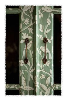 an old wooden door with floral designs painted on it and two metal handles in the middle