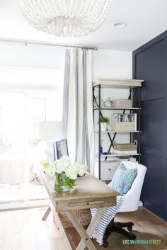 a living room with blue walls and white furniture in the center, along with a chandelier