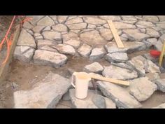 there is a bucket and shovel in the middle of this stone patio that's being built