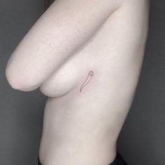 a woman's breast with a small tattoo on her left side, and a single flower in the middle