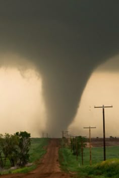 a large tornado rolls across the sky over a dirt road