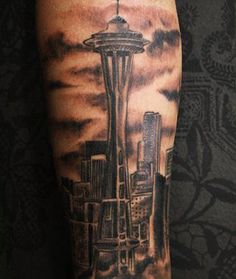 a man's arm with a black and grey tattoo on it, featuring the space needle