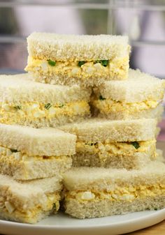 a stack of sandwiches sitting on top of a white plate next to a glass window