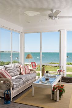 a living room filled with furniture and large windows overlooking the ocean on a sunny day