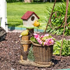 a birdhouse sitting on top of a basket next to flowers