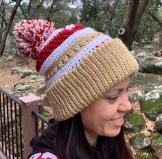 a woman sitting on a bench wearing a knitted hat with pom poms