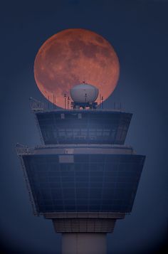 the moon is setting over an airport control tower