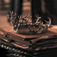 a crown sitting on top of a table next to a stack of folded books and napkins