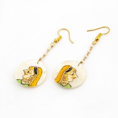 Introducing our exquisite collection of Hand Painted Mother of Pearl Earrings, a true reflection of Indian tradition and craftsmanship. These earrings feature real hand-painted artwork on mother of pearl, showcasing the rich cultural heritage and intricate work of its origin. The delicate hand-painted lady depicted on the mother of pearl exudes the essence of Indian culture and craftsmanship, adding a touch of elegance and charm to the earrings. Each piece is meticulously crafted with attention Elegant White Earrings For Navratri, Bollywood Style Brass Jewelry With Matching Earrings, Round Jewelry For Navratri Ceremonial Occasions, Traditional Brass Danglers, Bollywood Style Brass Round Jewelry, White Chandbali Jewelry For Navratri, Elegant White Jewelry For Navratri, Bollywood Style Round Brass Jewelry, Elegant White Jewelry With Artistic Design