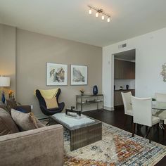 a living room filled with furniture next to a dining room table and chairs on top of a hard wood floor