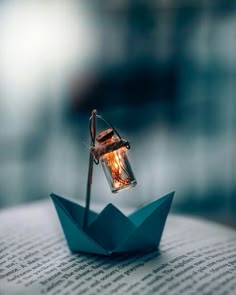 an origami boat with a light bulb in it sitting on top of a book