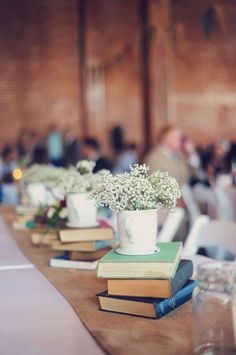 an instagram page with flowers in vases on top of books and people sitting at tables behind them