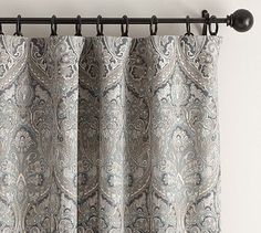 the curtain is hanging on the rod in front of the window with an ornate pattern