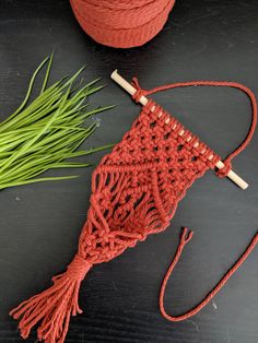 an orange crochet bag next to some green grass on a black surface with a wooden handle