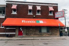 an old brick building with a red awning and the word roma written on it