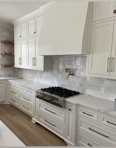 a kitchen with white cabinets and wood floors