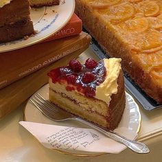 two slices of cake are sitting on plates with forks next to each other, along with books