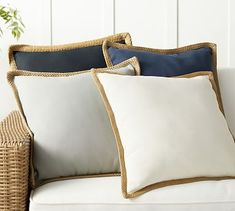 a white couch with pillows on it and a wicker basket next to the pillow