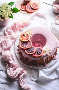 a cake with blood oranges on it sitting on a table next to other food