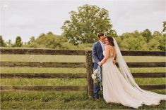 a bride and groom standing in front of a fence