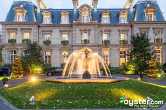 a fountain in front of a large building with lots of windows and lights on it