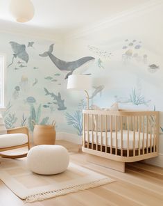 a baby's room with a crib, rocking chair, and wall mural