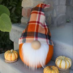 an orange and white gnome sitting next to pumpkins