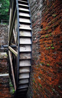 an old wooden water wheel on the side of a brick wall