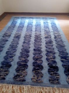 a blue and white rug sitting on top of a wooden floor next to a window