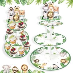 three tiered plates with cupcakes and jungle animals on them, surrounded by tropical leaves