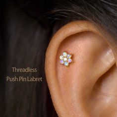 a close up of a person's ear with an opal flower in the middle