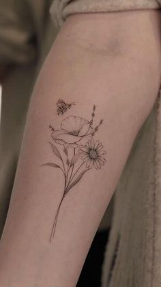 a woman's arm with flowers on it and a butterfly flying over the flower