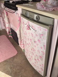 a kitchen with pink rugs on the floor and an old fashioned dishwasher