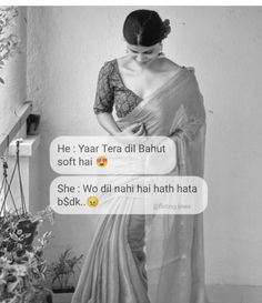 a woman in a sari is texting on her phone while standing next to a potted plant