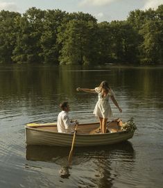 two people in a small boat on the water with trees in the backgroud