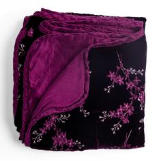 three purple and black bedspreads with white flowers on them are folded up in front of each other